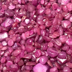 Puede incluir: Una vista de cerca de un mont&oacute;n de virutas de rub&iacute; rosa. Las virutas son de varios tama&ntilde;os y formas, con un acabado liso y pulido.