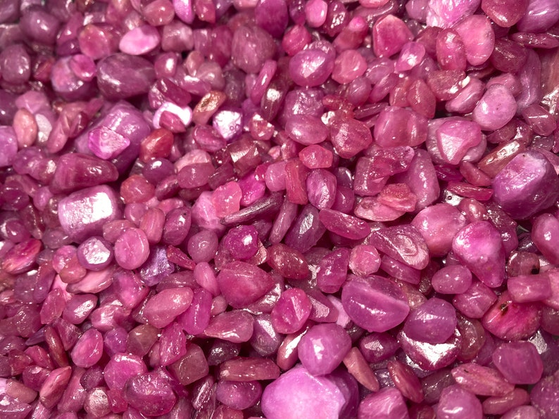 Puede incluir: Una vista de cerca de un mont&oacute;n de virutas de rub&iacute; rosa. Las virutas son de varios tama&ntilde;os y formas, con un acabado liso y pulido.