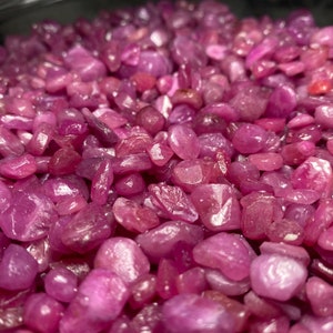 Puede incluir: Una vista de cerca de un mont&oacute;n de piedras preciosas de rub&iacute; rosa. Los rub&iacute;es son peque&ntilde;os y tienen una superficie lisa y pulida. Son de un color rosa vibrante y tienen un ligero brillo.