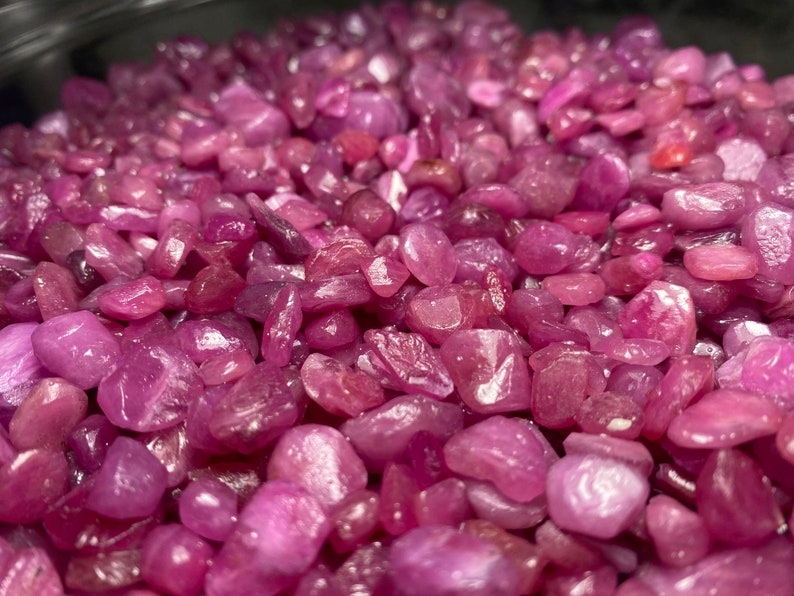 Puede incluir: Una vista de cerca de un mont&oacute;n de piedras preciosas de rub&iacute; rosa. Los rub&iacute;es son peque&ntilde;os y tienen una superficie lisa y pulida. Son de un color rosa vibrante y tienen un ligero brillo.