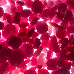 Puede incluir: Una vista de cerca de una colecci&oacute;n de piedras preciosas de rub&iacute; sueltas y facetadas. Los rub&iacute;es son de varios tama&ntilde;os y formas, con un color rojo intenso.