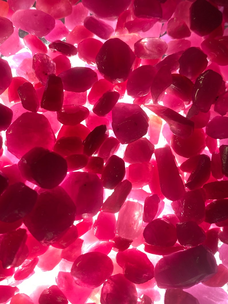 Puede incluir: Una vista de cerca de una colecci&oacute;n de piedras preciosas de rub&iacute; sueltas y facetadas. Los rub&iacute;es son de varios tama&ntilde;os y formas, con un color rojo intenso.