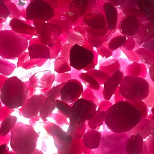 Puede incluir: Primer plano de un mont&oacute;n de piedras preciosas de rub&iacute; facetadas sueltas. Los rub&iacute;es son de varios tonos de rosa y rojo, y todos est&aacute;n pulidos y brillantes.