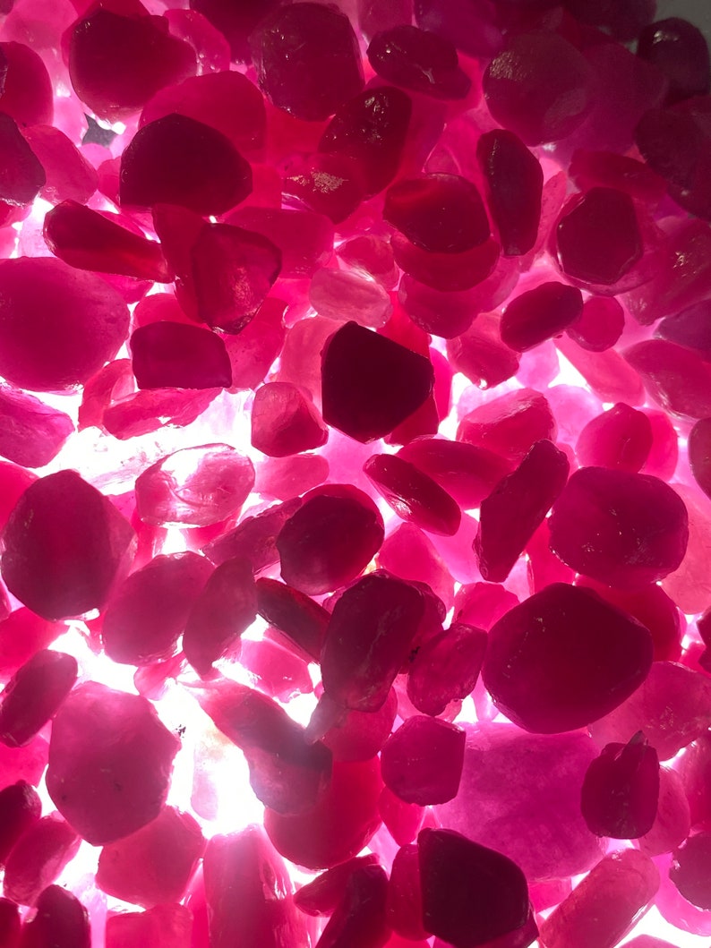 Puede incluir: Primer plano de un mont&oacute;n de piedras preciosas de rub&iacute; facetadas sueltas. Los rub&iacute;es son de varios tonos de rosa y rojo, y todos est&aacute;n pulidos y brillantes.