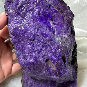 Puede incluir: Una piedra natural grande, rugosa, de color púrpura. La piedra tiene un color púrpura profundo y rico y una superficie texturizada.