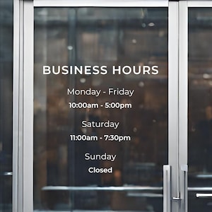 May include: A white sign on a glass door with the text "BUSINESS HOURS" and the hours of operation for each day of the week.
