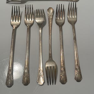 May include: Set of seven silver forks with ornate handles. The forks are all the same style and have a traditional design.
