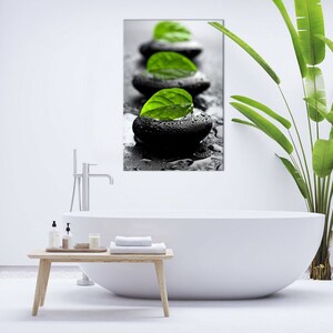 K&ouml;nnte beinhalten: Ein Schwarzwei&szlig;foto von glatten, nassen, schwarzen Steinen mit gr&uuml;nen Bl&auml;ttern darauf. Die Steine sind in einer Reihe auf einer schwarzen Oberfl&auml;che angeordnet.