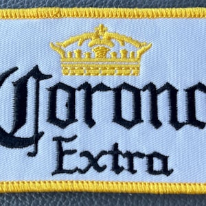 May include: A white ceramic mug with a black handle and the text "But First, Coffee" in a bold, black font. The mug is set against a blurred background, suggesting a cozy setting.