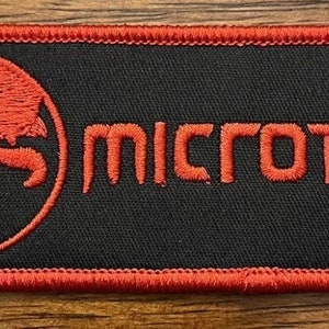 May include: Red embroidered patch with a black background. The patch features a red logo of a stylized scorpion inside a circle and the word "Microtech" in red.