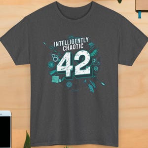 May include: A dark gray t-shirt with a teal graphic design. The graphic features the number 42 with the text "Intelligently Chaotic" above it.