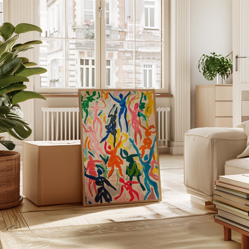May include: A framed abstract art print featuring a colorful design of dancing figures in shades of pink, blue, yellow, green, and orange. The print is set against a white background and framed in a natural wood frame.