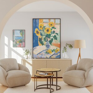 May include: Two beige armchairs with a wooden floor and a rug. A wooden table with a glass top sits between the chairs. A large painting of sunflowers in a vase sits above a wooden cabinet with a chevron pattern. A smaller painting of a landscape with a window frame is on the wall to the left of the large painting. A floor lamp with a beige shade and a wooden tripod base is to the right of the chairs.