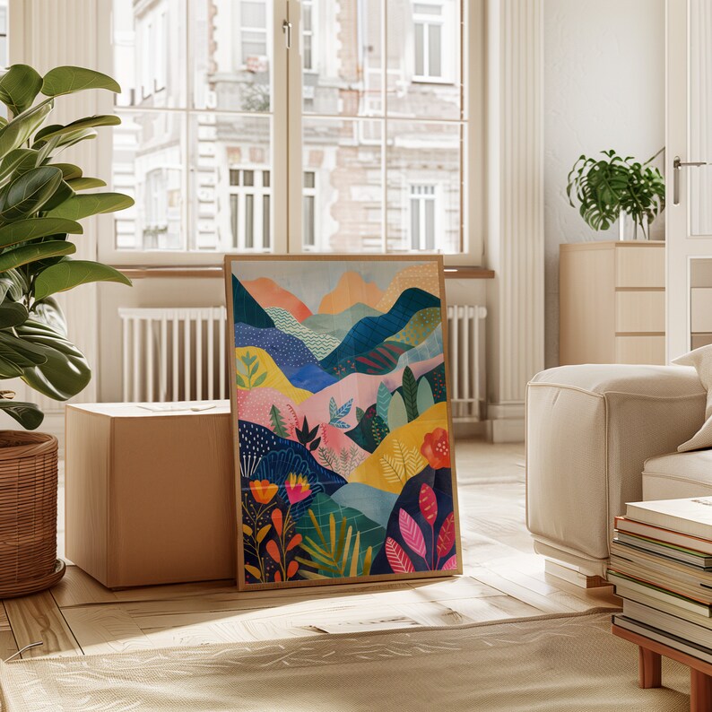 May include: A framed art print showcasing an abstract landscape design. The artwork presents rolling hills and mountains in shades of blue, yellow, orange, and green, with floral and plant details. The print is displayed in a light-coloured wooden frame.