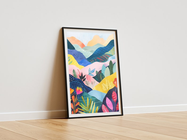 May include: A framed art print with a vibrant landscape illustration. The artwork shows rolling hills and mountains in shades of blue, pink, yellow, and orange, with detailed floral and foliage elements. The print is set in a black frame.