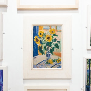 May include: A framed painting of a vase of sunflowers in a room with a window. The vase is blue and white with a floral pattern. The sunflowers are yellow with brown centers. The background is a light blue and orange.