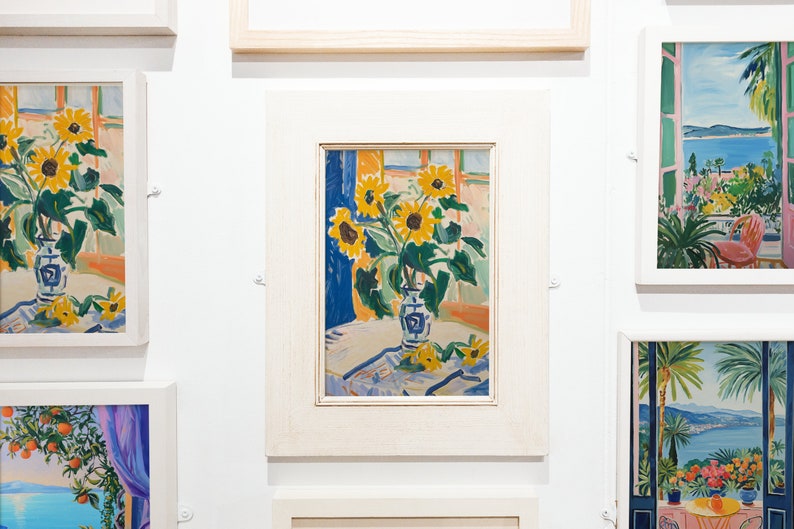 May include: A framed painting of a vase of sunflowers in a room with a window. The vase is blue and white with a floral pattern. The sunflowers are yellow with brown centers. The background is a light blue and orange.