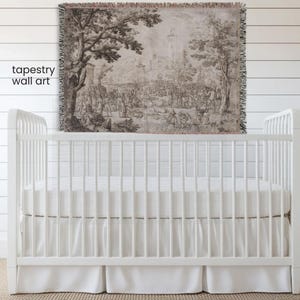 May include: A woven tapestry wall art featuring a detailed monochromatic landscape scene with trees, buildings, and numerous figures. The rectangular textile has a fringed edge and displays a historical illustration in shades of brown and beige.