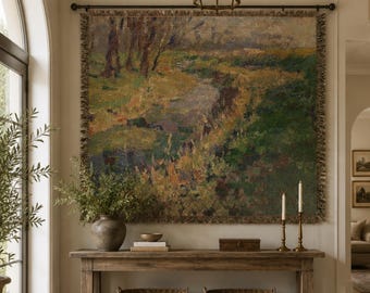 May include: A large rectangular woven wall tapestry featuring an impressionistic landscape painting of a grassy field with trees and a winding path, finished with a fringed border and suspended from a dark metal rod on a light-colored wall.