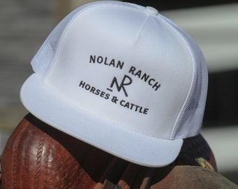 Może przedstawiać: Biała czapka trucker z haftowanym czarnym logo z napisem "Nolan Ranch - NR Horses & Cattle"