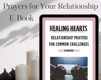 May include: A pink and white digital tablet with the text "HEALING HEARTS" and "RELATIONSHIP PRAYERS FOR COMMON CHALLENGES" on the screen. The text "E-BOOK" appears twice on the screen. The tablet is on a white surface with three white candles and a wooden tray with black figs.