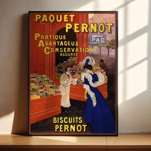 Puede incluir: Anuncio vintage para las galletas Paquet Pernot. El cartel presenta un fondo rojo con texto amarillo que dice "Paquet Pernot" y "Biscuits Pernot". El cartel también presenta a una mujer con un vestido azul y un hombre con una bata blanca de pie frente a una pantalla de galletas.