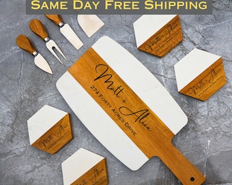 May include: A white and brown wooden serving board with a handle. The board is engraved with the names "Matt + Alice" and the address "274 Forty Acres Drive". The board is surrounded by four smaller white and brown wooden coasters with the same engraving.