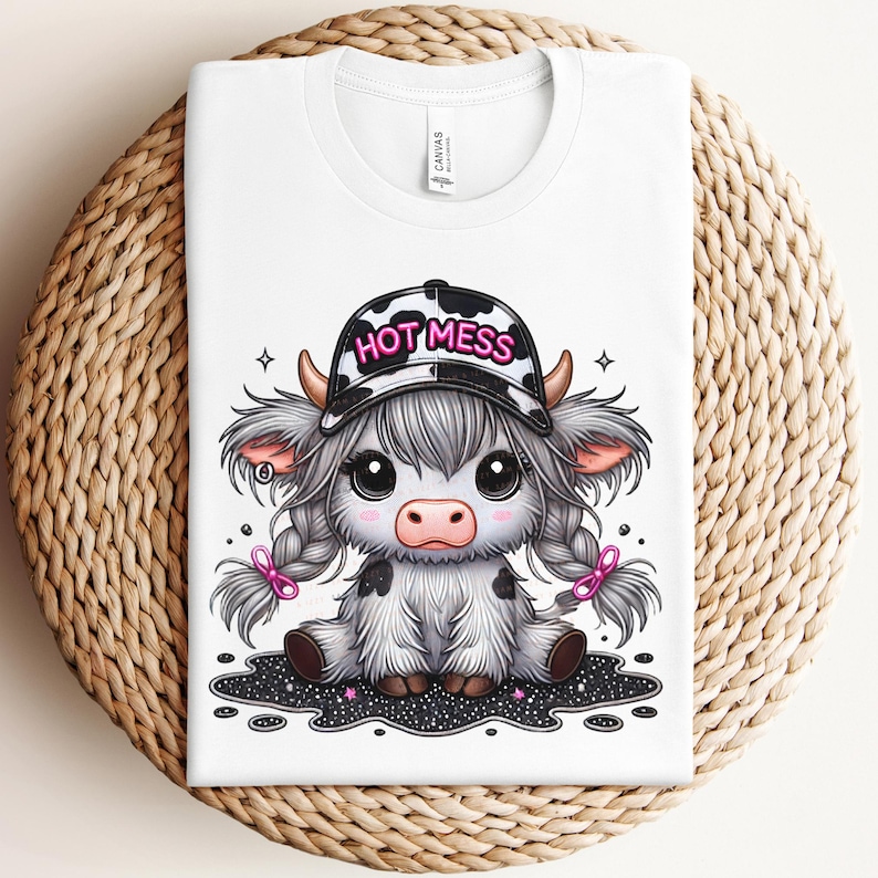 May include: White t-shirt with a cartoon illustration of a cow wearing a black and white baseball cap that says "HOT MESS". The cow has black and white spots and pink pigtails.