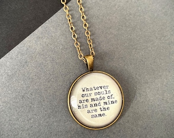 May include: A gold chain necklace with a round pendant featuring the quote "Whatever our souls are made of, his and mine are the same."