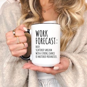 May include: White ceramic mug with black handle and rim. The mug features the text "WORK FORECAST: BUSY. SCATTERED SARCASM WITH A STRONG CHANCE OF MUTTERED PROFANITIES." A humorous and relatable office or home accessory.