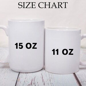 May include: Two white ceramic mugs, one 15 oz and one 11 oz, side by side on a light wood surface.