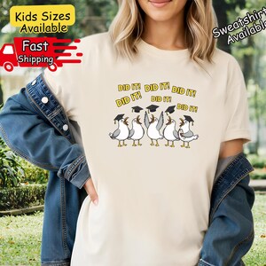 May include: Ivory-colored t-shirt featuring a graphic of cartoon seagulls wearing graduation caps, with the text "DID IT!" above them. The shirt also has the text "Kids Sizes Available" and "Sweatshirts Available".