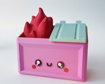 May include: A pink box with a smiling face and a red flame on top. The box has a light blue lid with a textured surface.