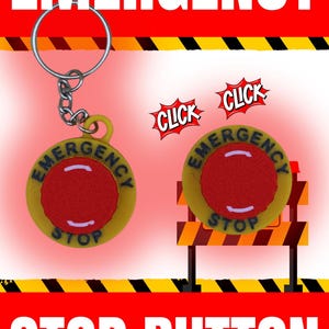 Puede incluir: Un llavero de botón de parada de emergencia amarillo y rojo con las palabras "Emergency Stop" y "Click" en él. El llavero está unido a un llavero plateado.