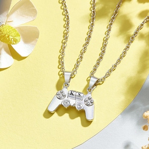May include: Two silver necklaces with a silver video game controller pendant. The controller has the letters "K" and "S" on it.