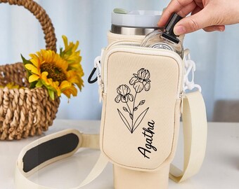 May include: A beige insulated beverage holder with a shoulder strap and a zippered pocket. The holder has a floral design and the name "Agatha" printed on it.