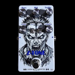 Könnte beinhalten: Ein weißes Gitarreneffektpedal mit einer schwarz-weißen Illustration eines grinsenden Zombigesichts. Das Pedal hat sechs silberne Regler mit der Beschriftung Bass, Mid, Treble, Gain, Attack, Si/Ge und Volume sowie den Aufdruck Z-TONE und LAND MINE EFFECTS.