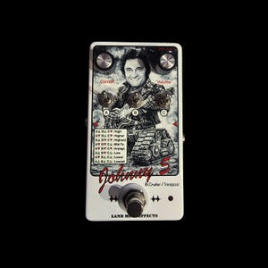 Puede incluir: Pedal de efectos de guitarra blanco con una imagen en blanco y negro de un músico tocando la guitarra. El pedal tiene perillas con las etiquetas "Control" y "Volume", y el texto "Johnny 5" y "Bit Crusher / Transposer".