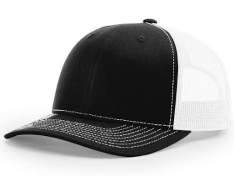 May include: A black and white trucker hat with a black front panel and a white mesh back panel. The hat has a curved brim and a white stitching detail around the brim.