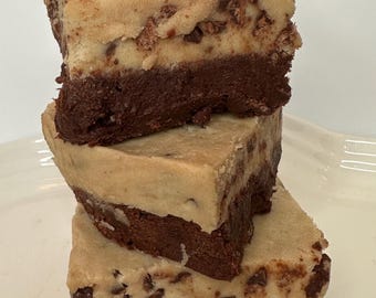 May include: A stack of three brownie cookie dough bars. Each bar has a layer of chocolate brownie topped with a layer of cookie dough. The cookie dough is studded with chocolate chips.