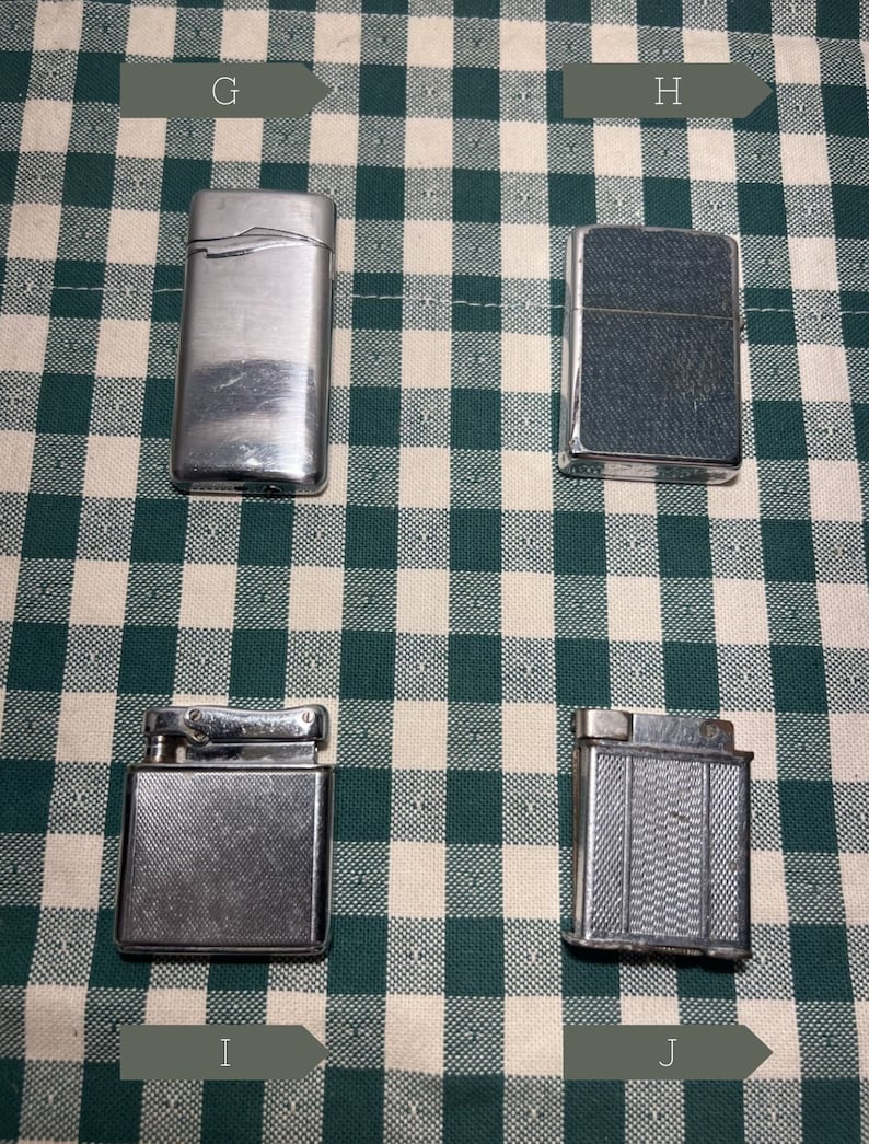 May include: Four silver lighters on a green and white checkered background. The lighters have different designs and textures.