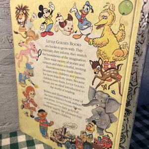 May include: A yellow book cover with the title "Little Golden Books" and a description of the books. The cover features illustrations of popular children's characters including Mickey Mouse, Donald Duck, Big Bird, and a pink panther.