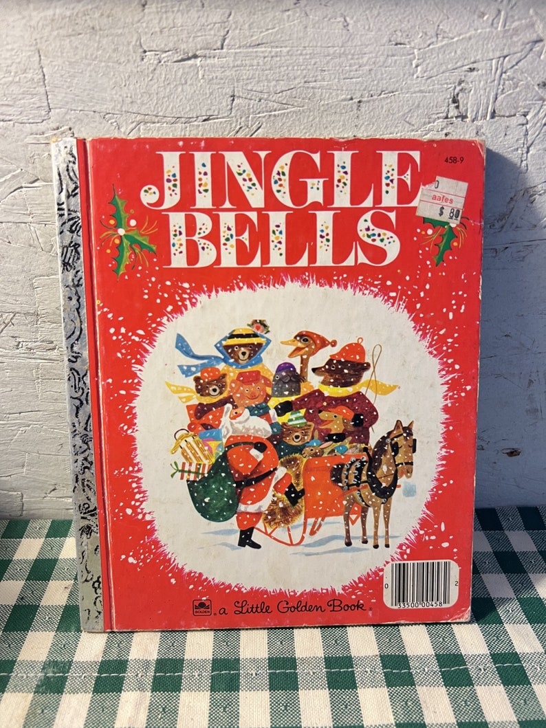 May include: A vintage Little Golden Book titled "Jingle Bells" with a red cover featuring a colourful illustration of Santa Claus and animals riding in a sleigh. The book has a price tag of &pound;0.80.