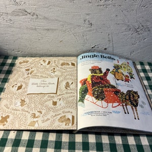 May include: A vintage Little Golden Book titled "Jingle Bells" with illustrations of bears in a sleigh. The book cover is white with red and green accents. The book is open to the last page, which shows a copyright notice and a note that says "This Little Golden Book belongs to..."
