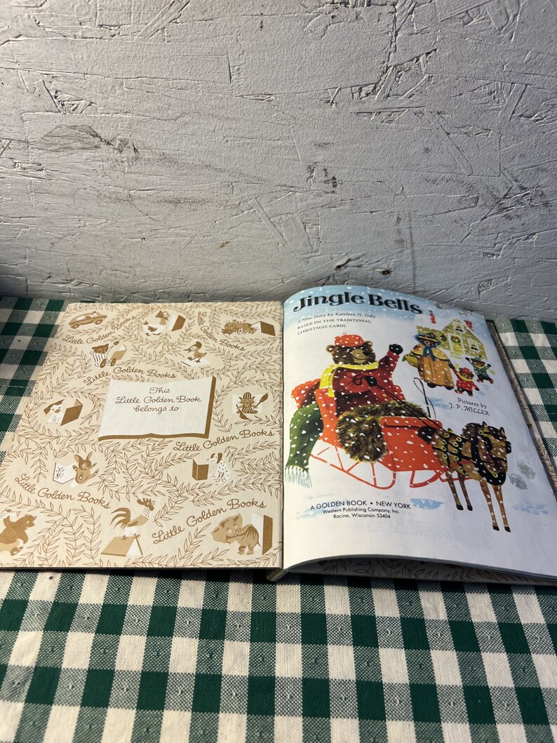 May include: A vintage Little Golden Book titled "Jingle Bells" with illustrations of bears in a sleigh. The book cover is white with red and green accents. The book is open to the last page, which shows a copyright notice and a note that says "This Little Golden Book belongs to..."