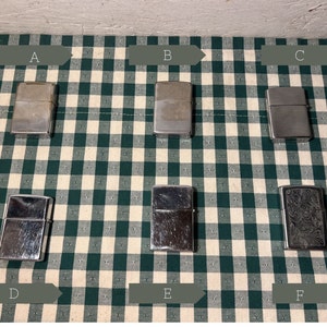 May include: Six silver lighters on a green and white checkered surface. The lighters are labeled A through F.