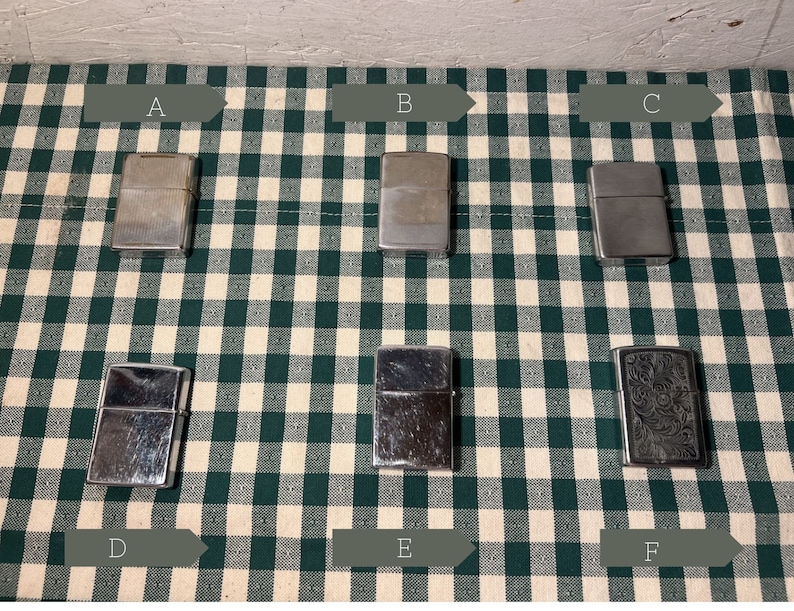 May include: Six silver lighters on a green and white checkered surface. The lighters are labeled A through F.