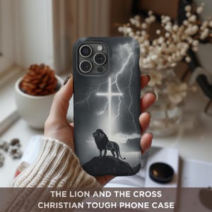 May include: A black phone case with a graphic of a lion standing in front of a cross with lightning bolts in the background. The text "The Lion and the Cross" is printed on the case.