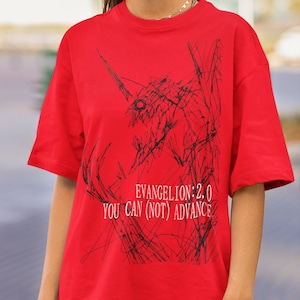 以下が含まれることがあります： 赤いTシャツ。黒い生き物のグラフィックと「EVANGELION 2.0 YOU CAN (NOT) ADVANCE」の文字がプリントされています。Tシャツは半袖で、クルーネックです。