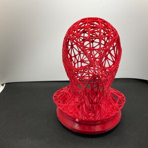 Könnte beinhalten: Ein rot 3D-gedrucktes Modell eines Kopfes mit einem netzartigen Design. Das Modell ist hohl und hat eine runde Basis.